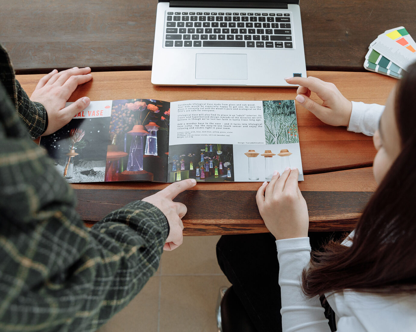 Deux personnes consultent une brochure imprimée devant un ordinateur portable